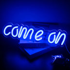 Bilden har en levande LED-neonskylt som visar orden "Come On" i ett djärvt och lekfullt manustypsnitt.