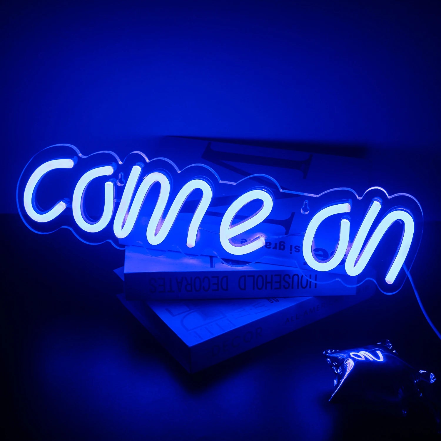 The image features a vibrant LED neon sign displaying the words "Come On" in a bold and playful script font.