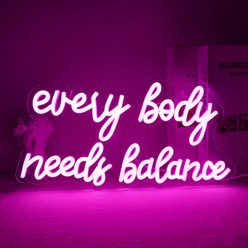 Bilden visar en levande "Every Body Needs Balance" LED-neonskylt.