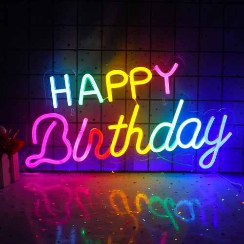En livlig "Happy Birthday" LED neonskylt i festliga färger monterad på en vägg.