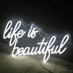 A vibrant, handmade LED neon sign displaying the phrase "Life is Beautiful" in elegant, flowing script.