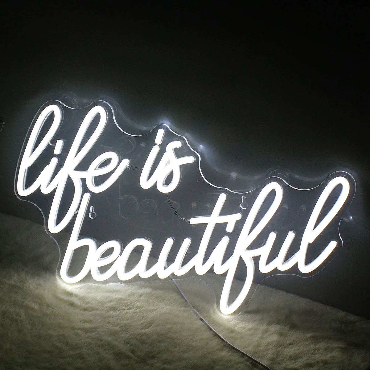 En levande, handgjord LED-neonskylt som visar frasen "Life is Beautiful" i elegant, flytande manus.