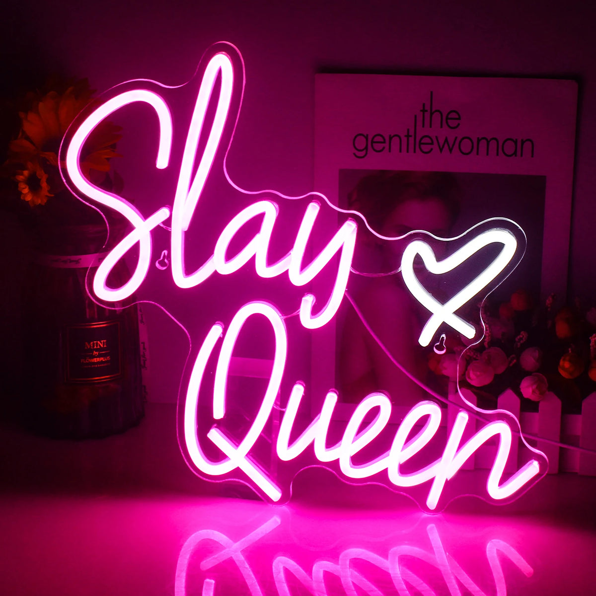 Bilden har en levande LED-neonskylt som visar orden "Slay Queen" med eleganta, kursiva bokstäver.