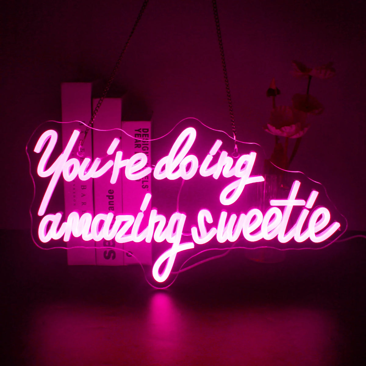 En livlig LED-neonskylt som visar frasen "You're Doing Amazing Sweetie" i elegant, kursiv handstil.