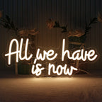 Bilden visar en handgjord LED-neonskylt med orden "All We Have Is Now" i livfulla, självlysande bokstäver.