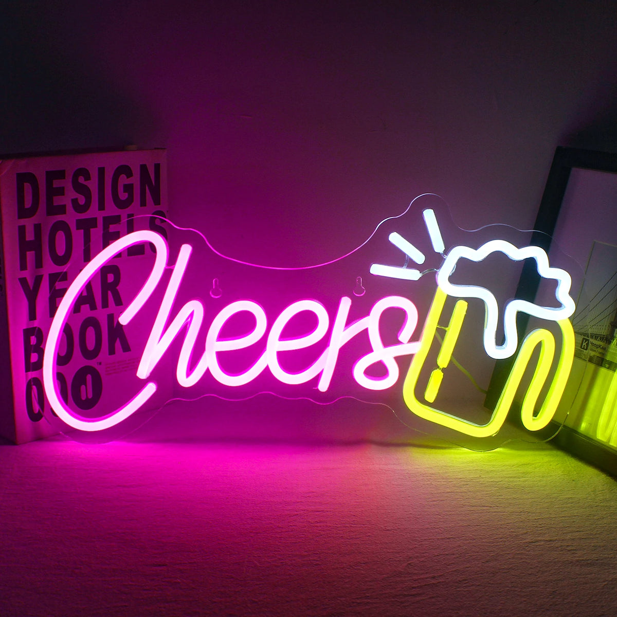 Bilden har en levande "Cheers" LED-neonskylt upplyst mot en mörk bakgrund.