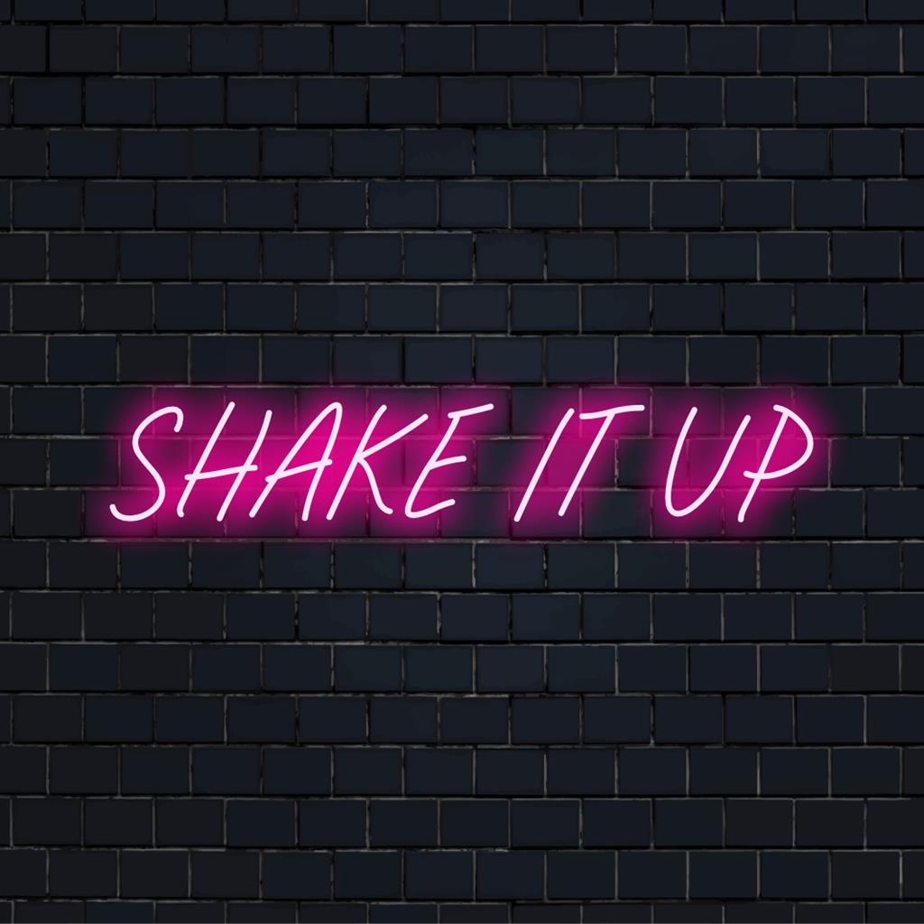 Energisk orange och rosa LED-neonskylt med orden Shake It Up, som förkroppsligar vibrerande energi och feststämning.