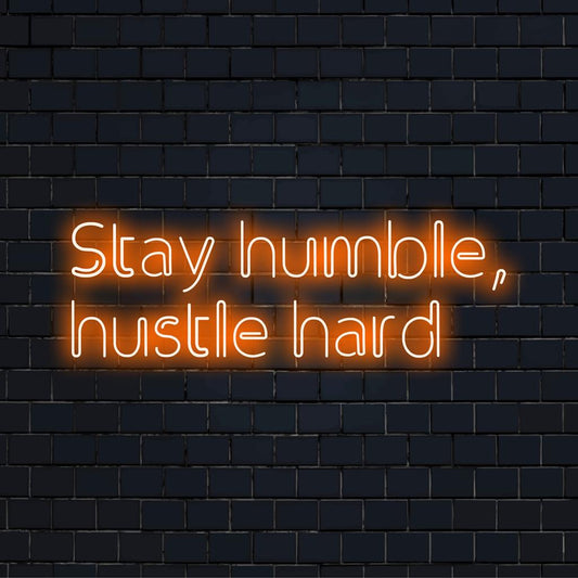 Custom LED sign displaying 'Stay Humble, Hustle Hard'; perfect blend of artistic inspiration and chic neon decor ambiance.