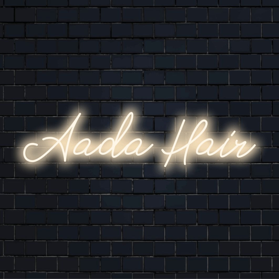 Aada Hair Custom Name Neon Sign, glowing lettering on dark brick wall