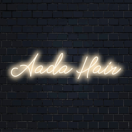Aada Hair Custom Name Neon Sign, glowing lettering on dark brick wall