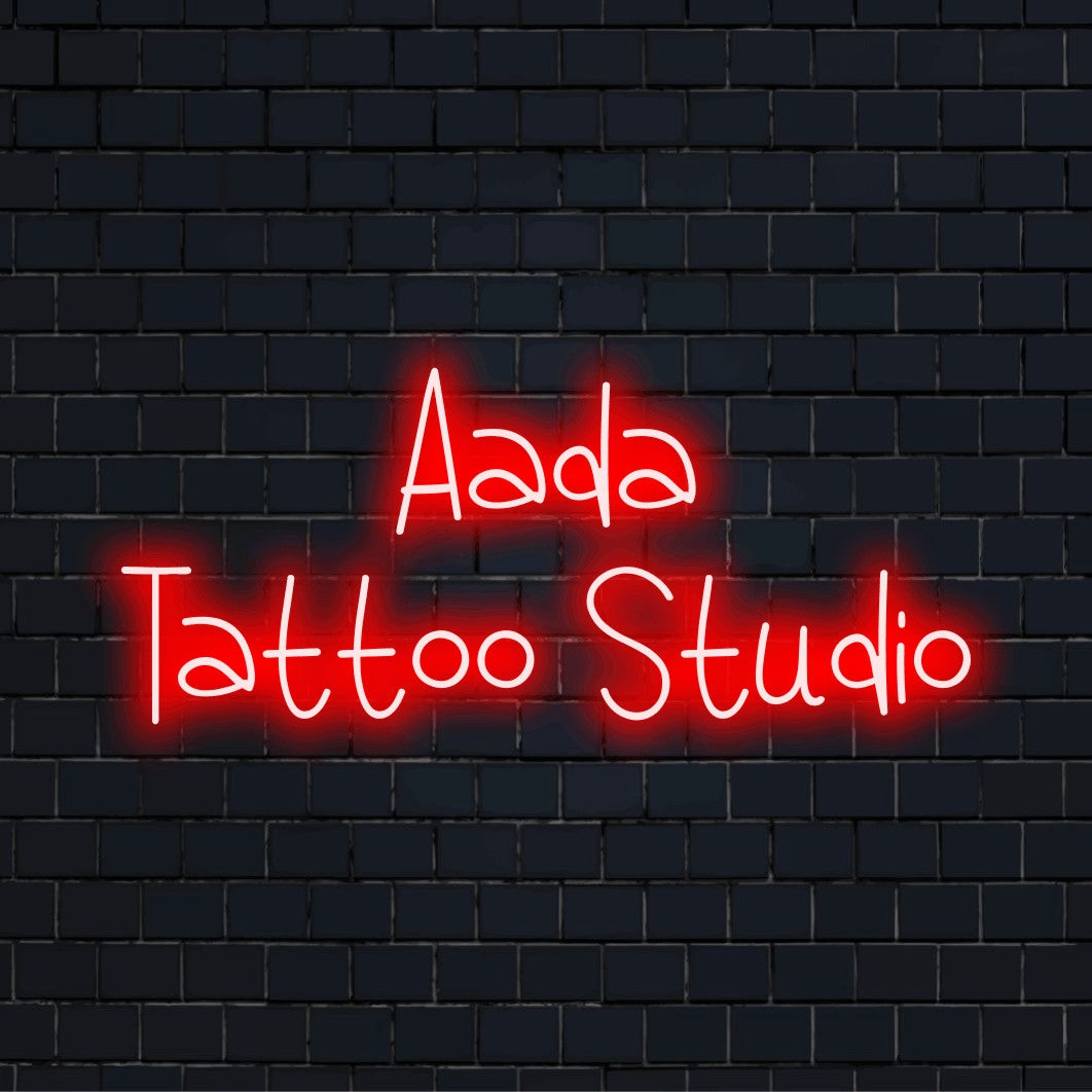 Aada Tattoo Studio Custom Name Neon Sign, bright neon glow on black brick background