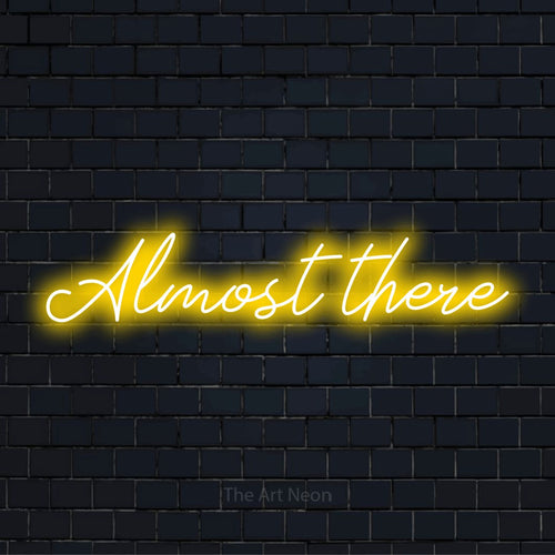"Almost There" neon text design on a black brick wall
