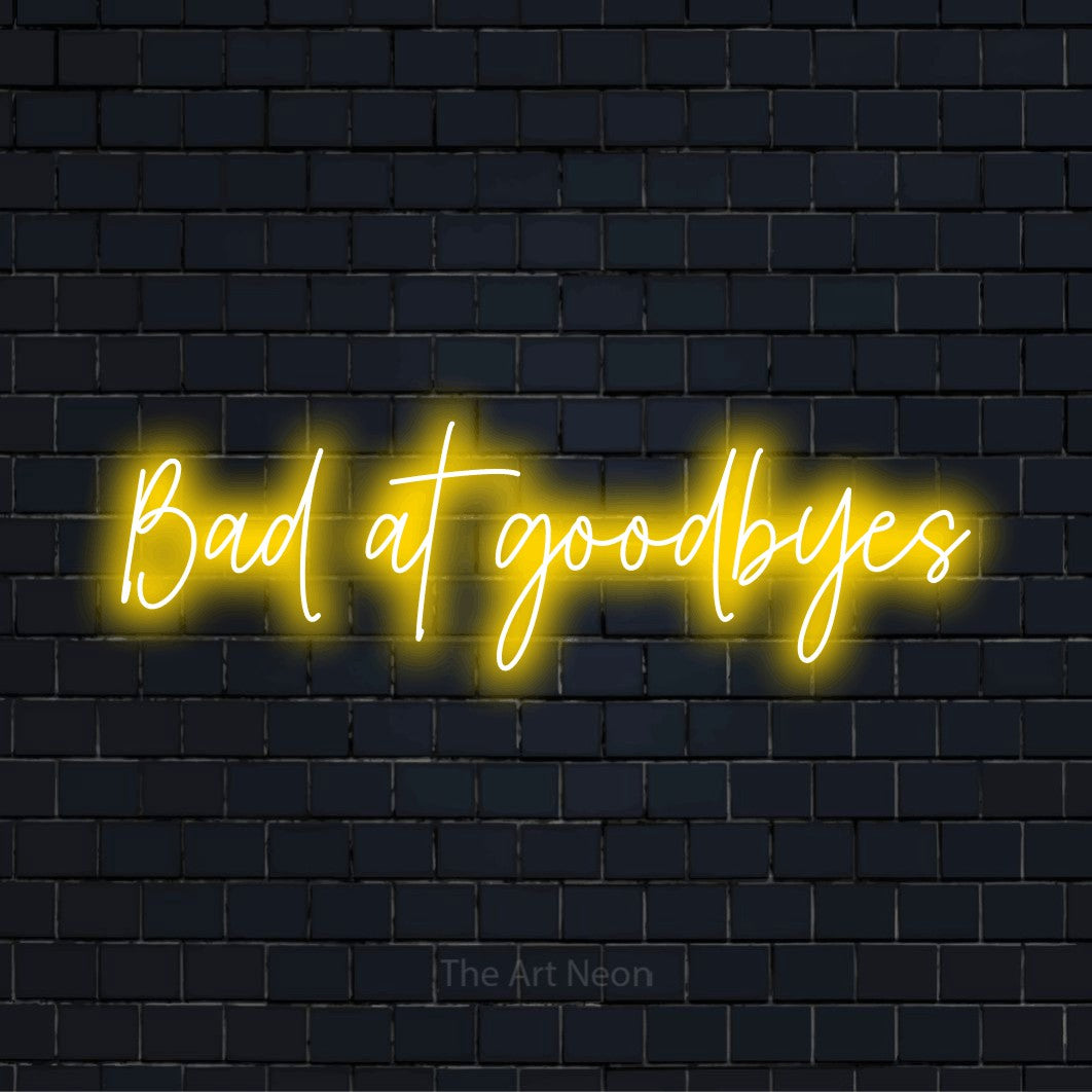 "Bad At Goodbyes" LED neon sign on a black brick wall