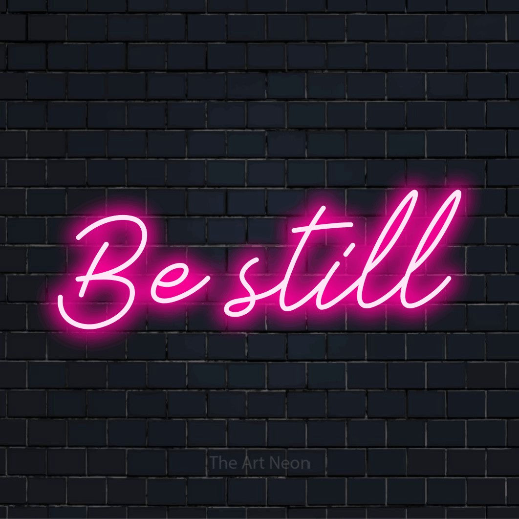 "Be Still" neon text design on a black brick wall