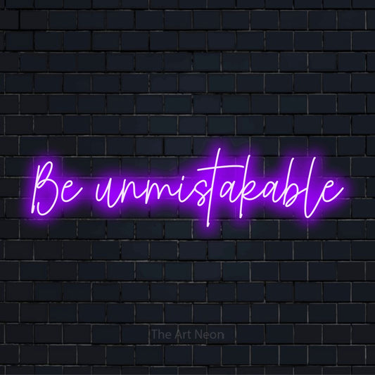 "Be Unmistakable" LED neon sign on a black brick wall