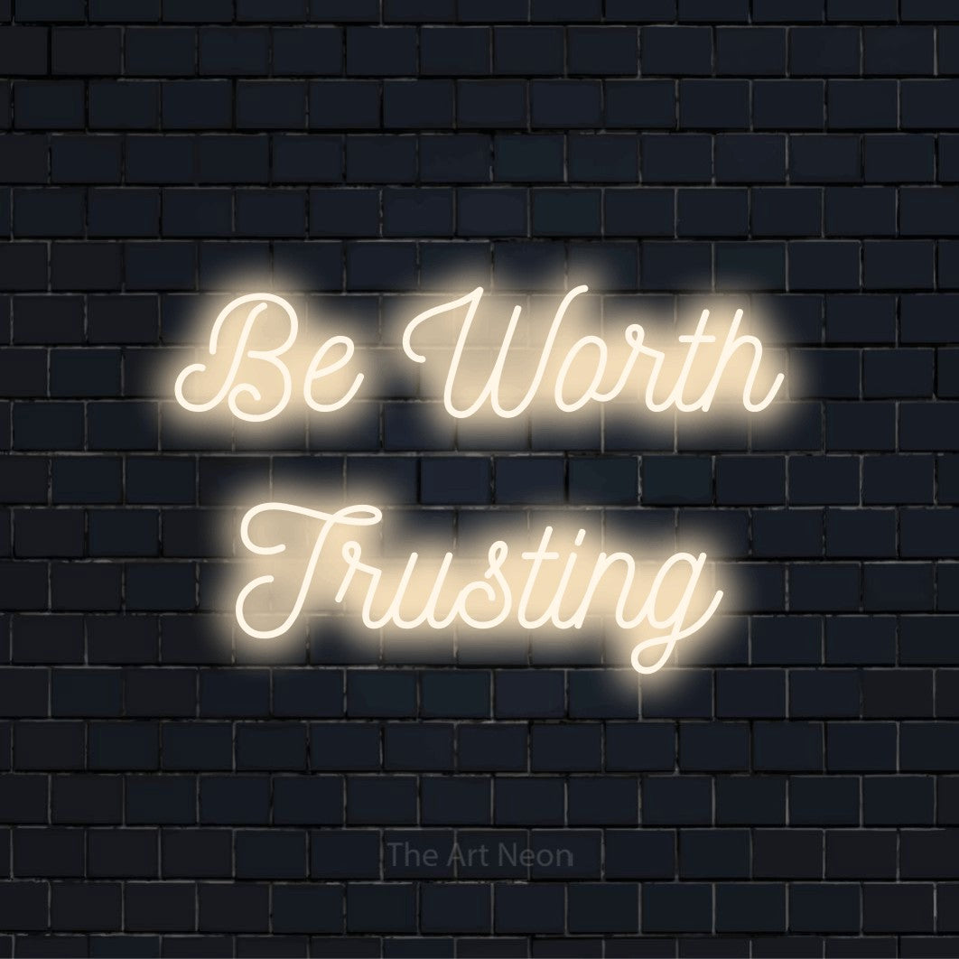 "Be Worth Trusting" glowing LED neon sign on a black brick wall