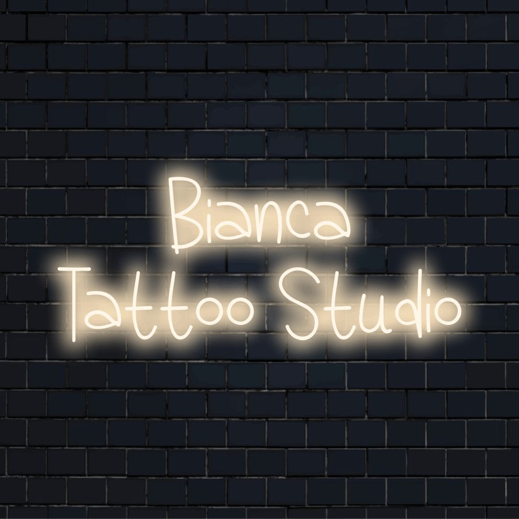 Bianca Tattoo Studio Personalized Neon Light with bright neon lettering on dark brick wall