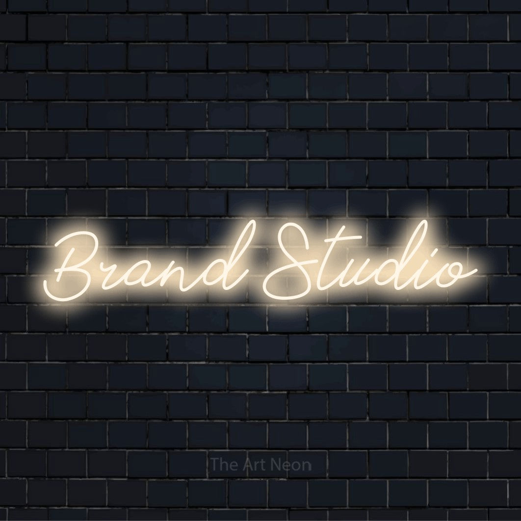 "Brand Studio" neon text design on a black brick wall