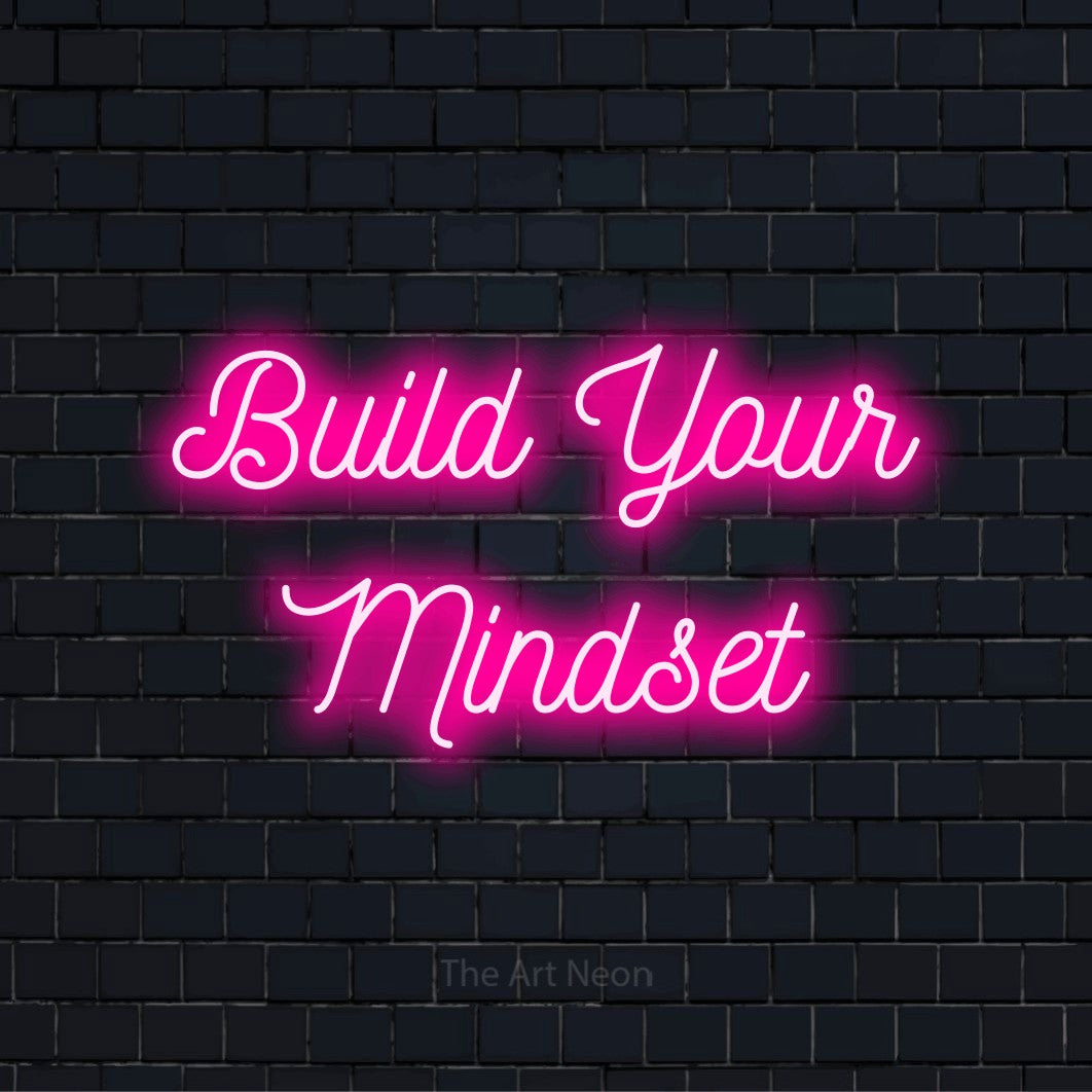 "Build Your Mindset" text design with neon effect on a black brick wall