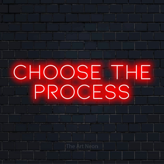 "Choose The Process" glowing LED neon sign on a black brick wall