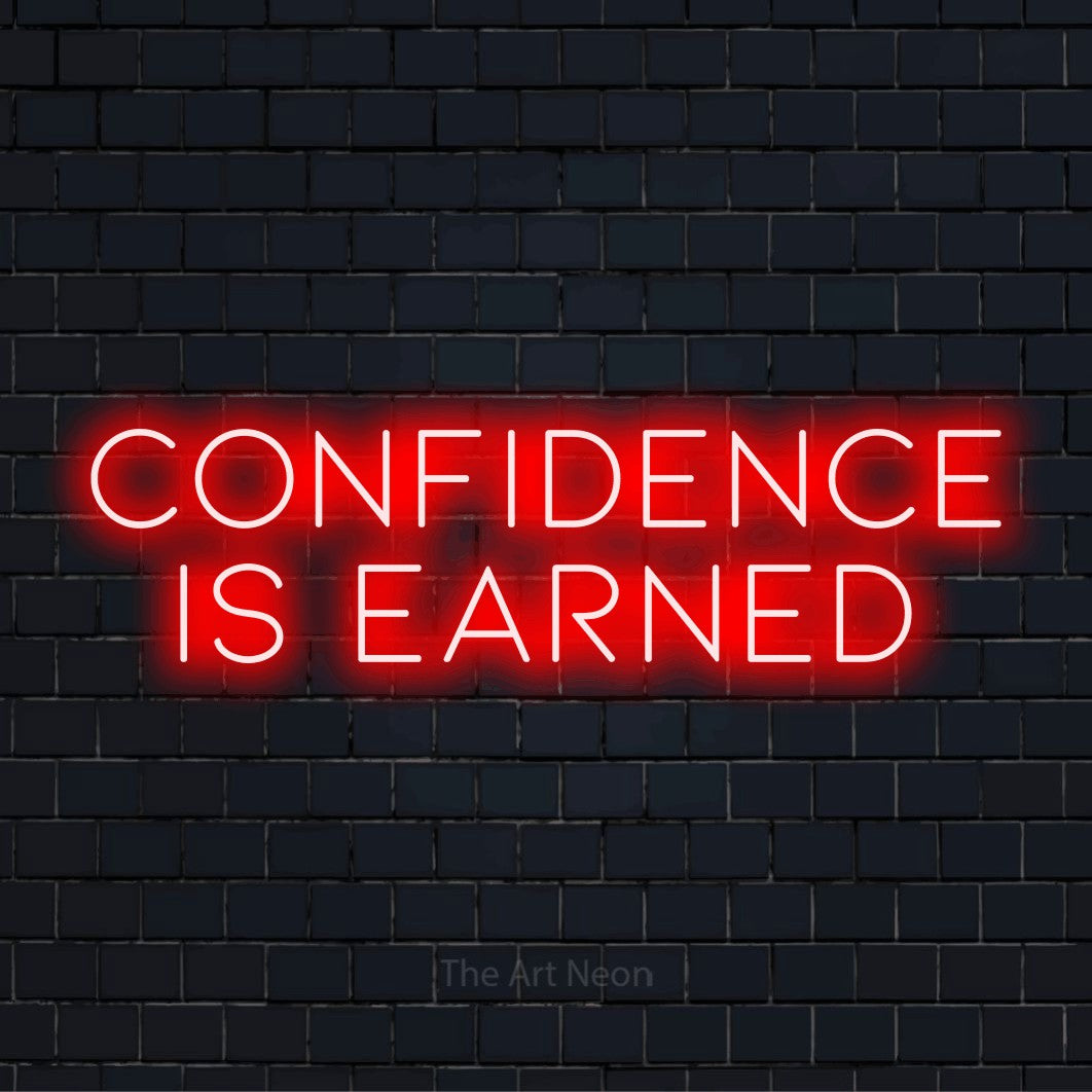 "Confidence Is Earned" script-style LED neon sign on a black brick wall