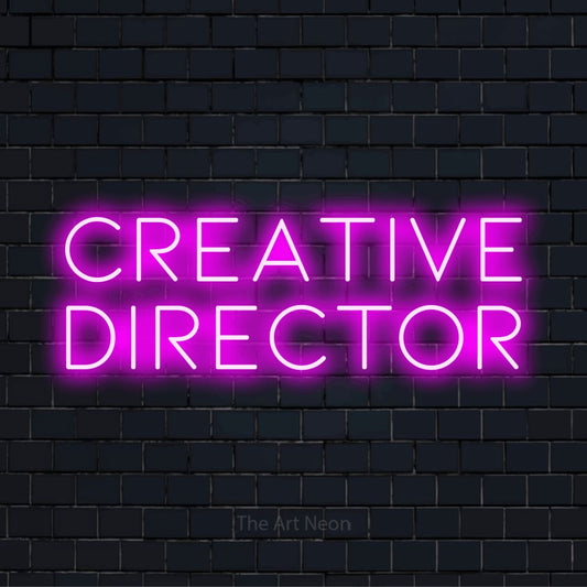 "Creative Director" script-style LED neon sign on a black brick wall