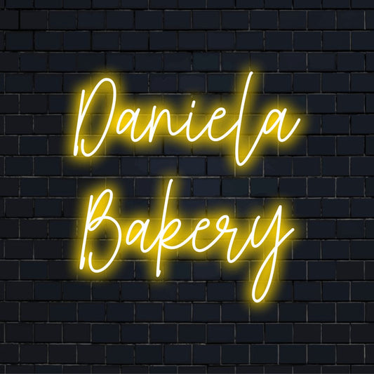 Daniela Bakery Custom Name Neon Sign, neon text light on dark brick wall