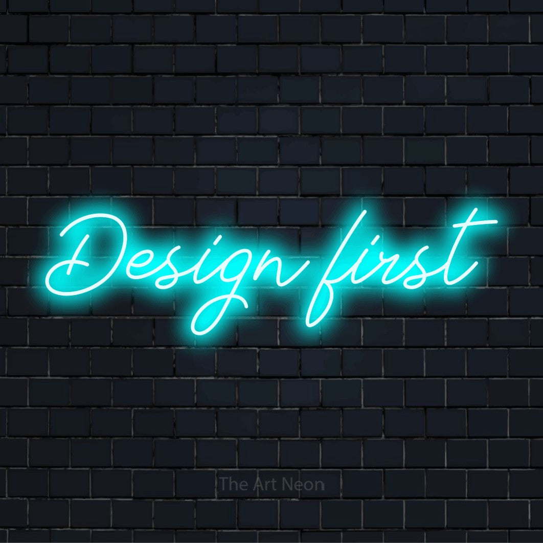 "Design First" neon text design on a black brick wall