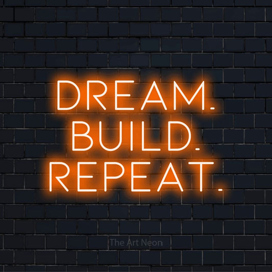 "Dream. Build. Repeat." glowing LED neon sign on a black brick wall