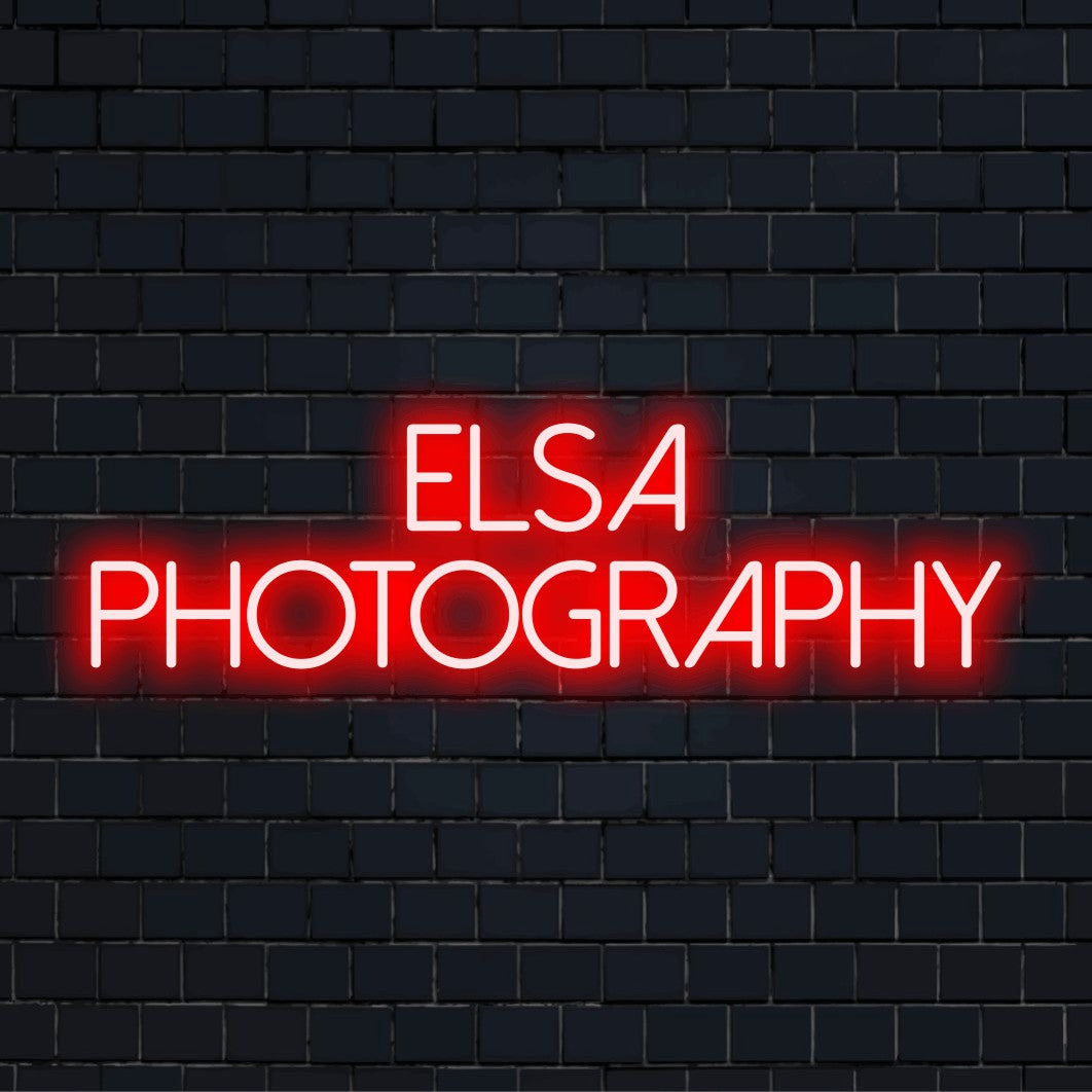 Elsa Photography Custom Name Neon Sign, glowing neon text on dark brick background