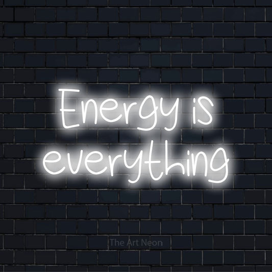 "Energy Is Everything" script-style LED neon sign on a black brick wall