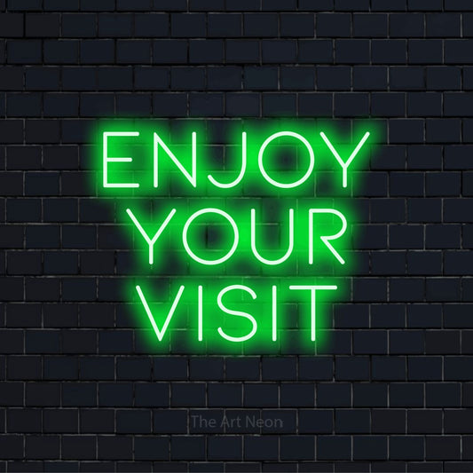 "Enjoy Your Visit" text design with neon effect on a black brick wall
