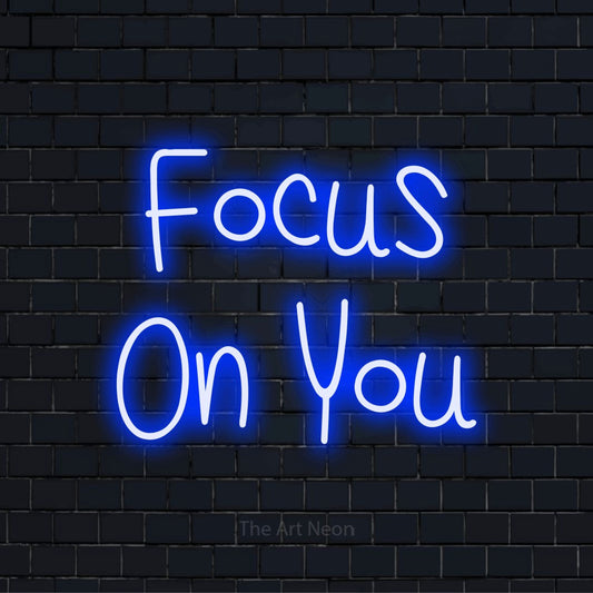 "Focus On You" script-style LED neon sign on a black brick wall