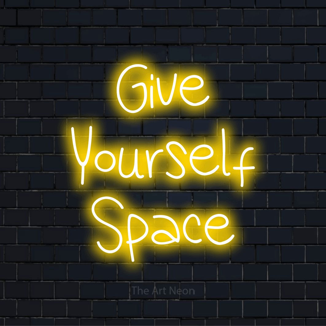 "Give Yourself Space" script-style LED neon sign on a black brick wall