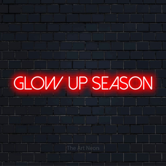 "Glow Up Season" glowing LED neon sign on a black brick wall