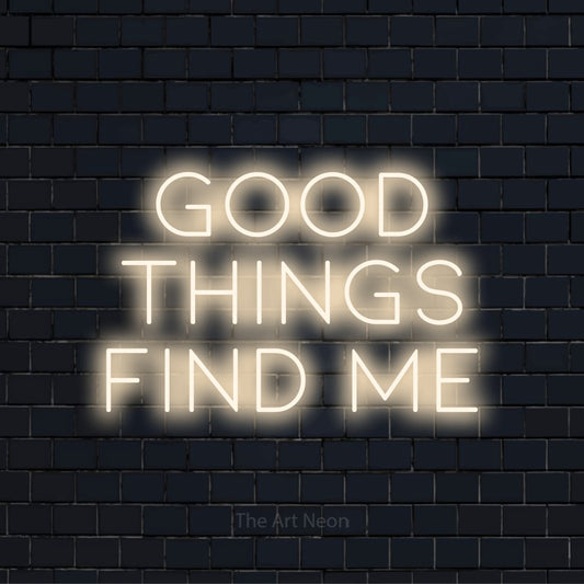 "Good Things Find Me" script-style LED neon sign on a black brick wall