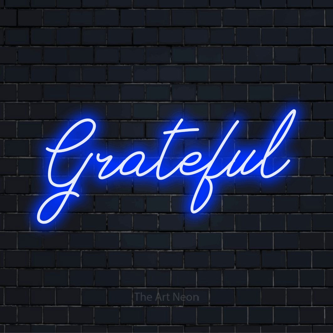 "Grateful" script-style LED neon sign on a black brick wall