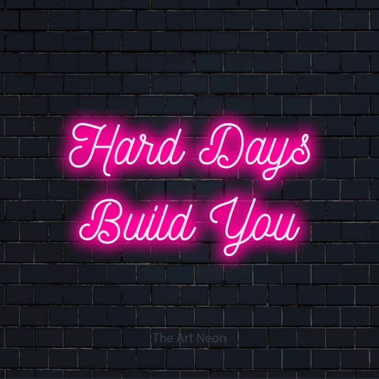 "Hard Days Build You" text design with neon effect on a black brick wall