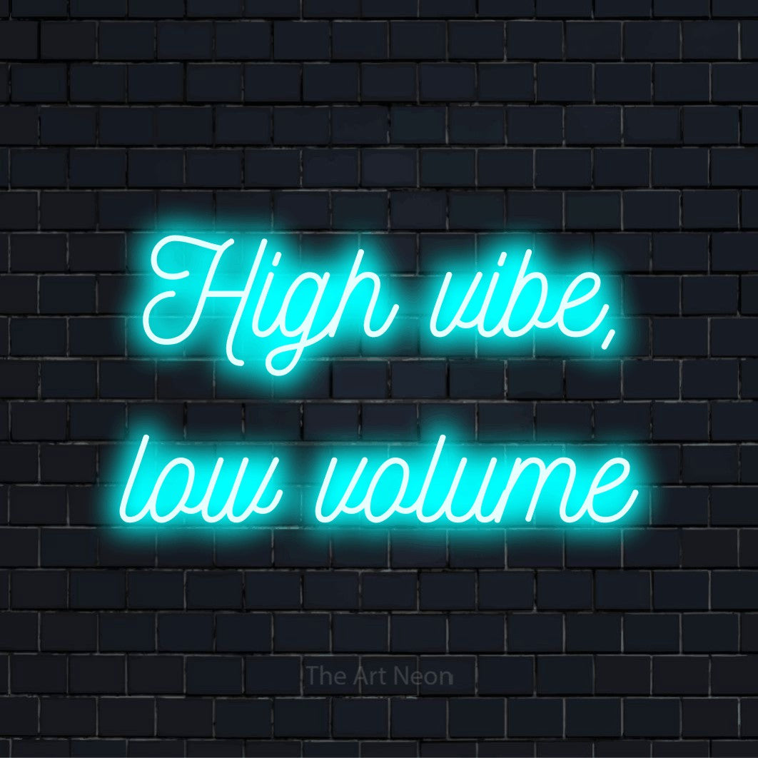 "High Vibe, Low Volume" text design with neon effect on a black brick wall