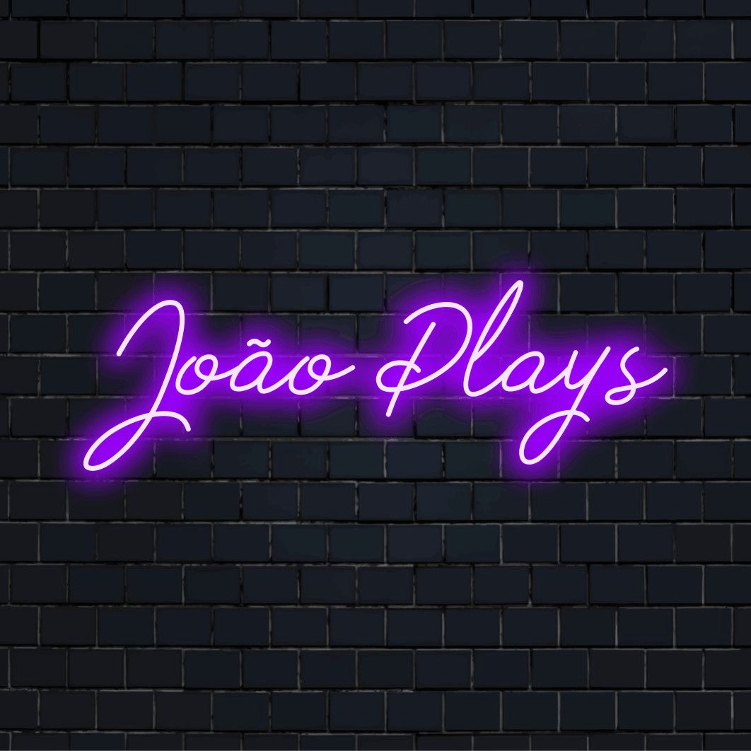 Joao Plays Personalized Neon Light with bright neon lettering against black brick wall