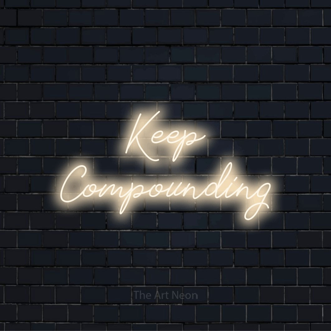 "Keep Compounding" glowing LED neon sign on a black brick wall