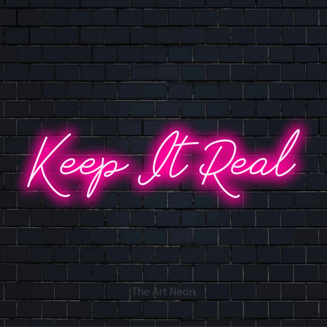 "Keep It Real" glowing LED neon sign on a black brick wall