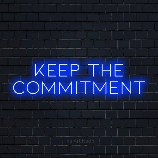 "Keep The Commitment" script-style LED neon sign on a black brick wall