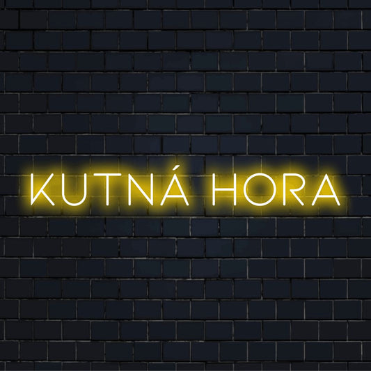 Kutn Hora Neon Sign, bright neon lettering against black brick wall