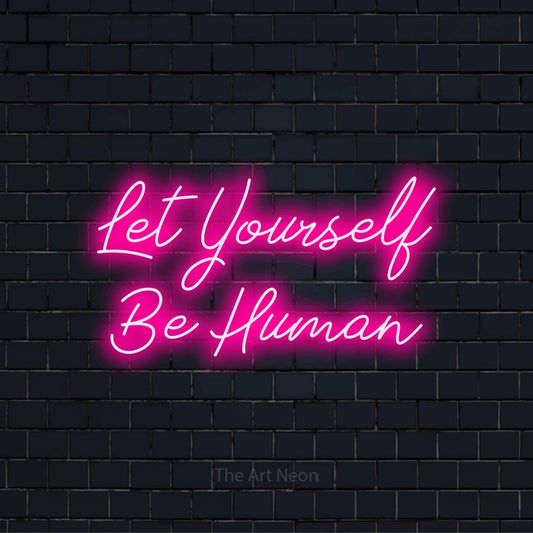 "Let Yourself Be Human" text design with neon effect on a black brick wall