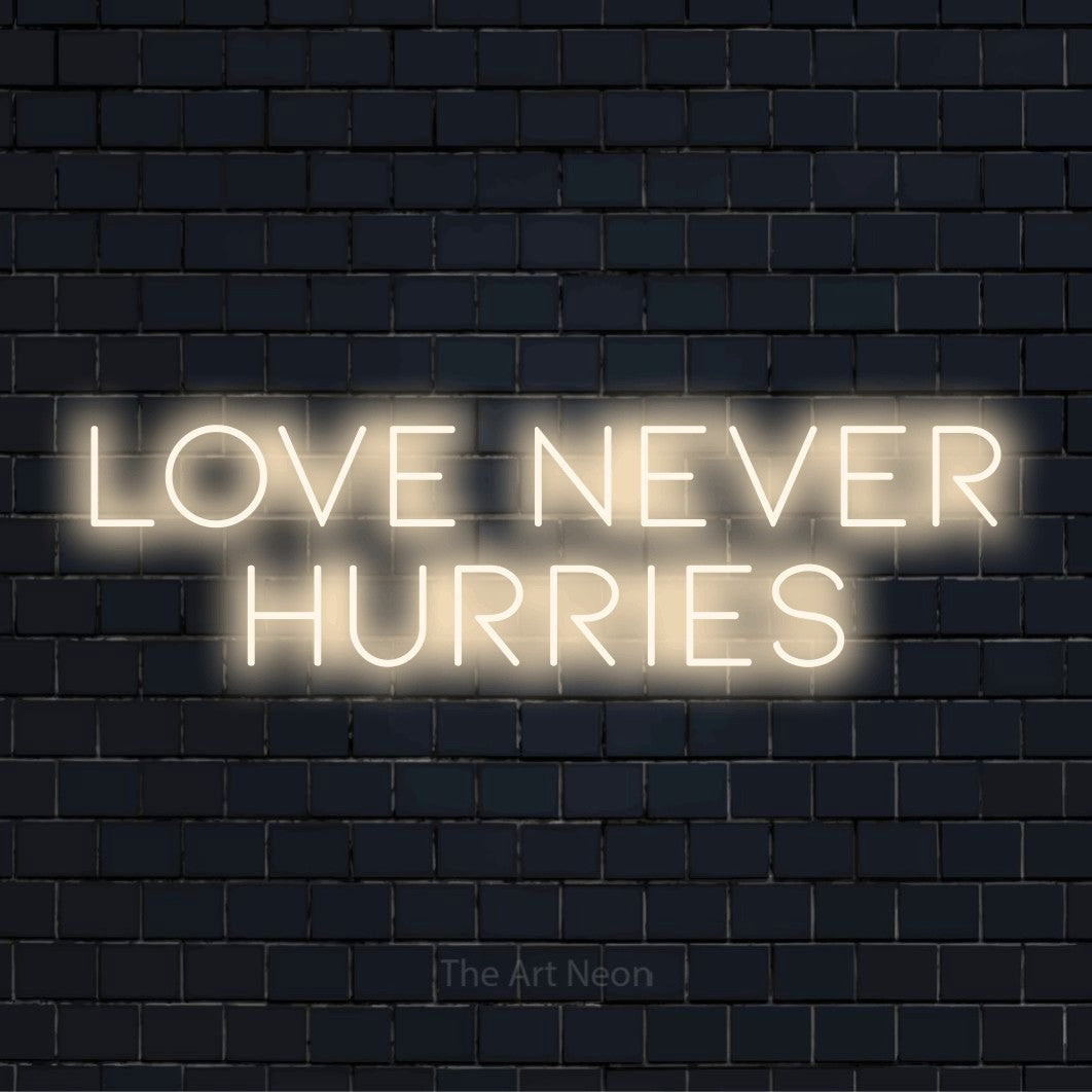 "Love Never Hurries" LED neon sign on a black brick wall