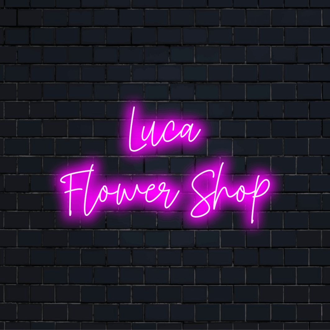 Luca Flower Shop Custom Name Neon Sign, bright neon lettering against black brick wall