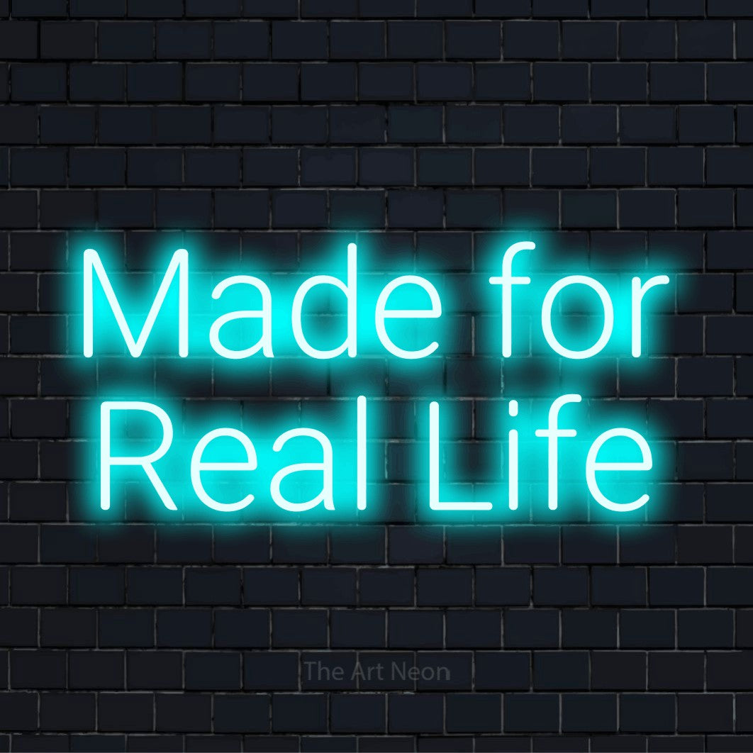 "Made For Real Life" LED neon sign on a black brick wall