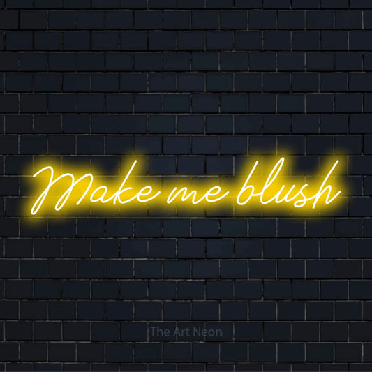 "Make Me Blush" LED neon sign on a black brick wall