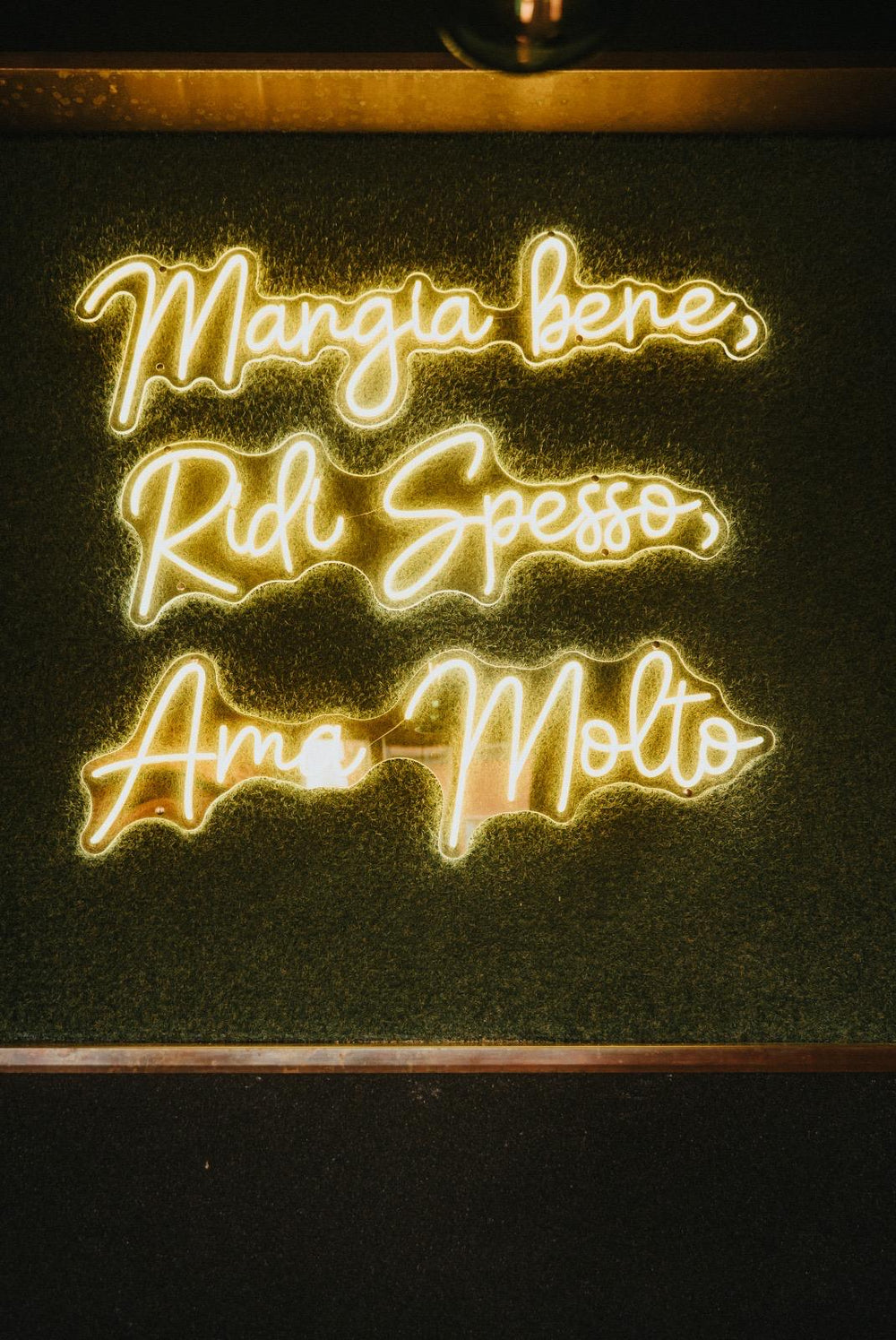 Green Mangia Bene Ridi Spesso LED neon sign in a restaurant interior
